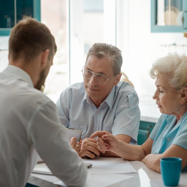 An older couple speaks with a real estate agent about a contract.