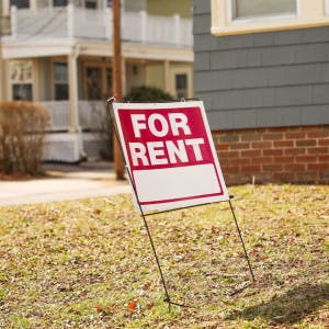 A for-rent sign in the yard in front of a house