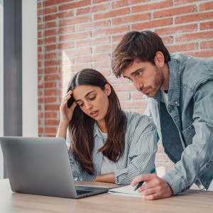 Frustrated young couple looks at laptop