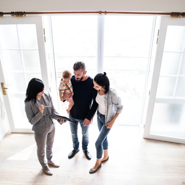 A real estate agents shows a home to a young couple with a baby