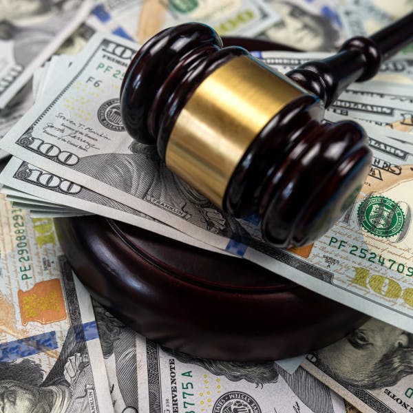 A judge's gavel on top of a pile of hundred-dollar bills