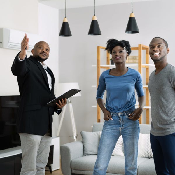 A Black real estate agent and Black couple view a home for sale.