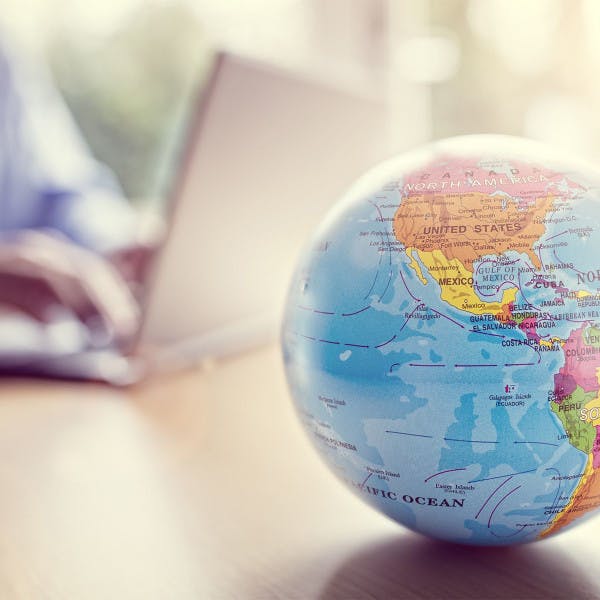 Globe on table; laptop user in background