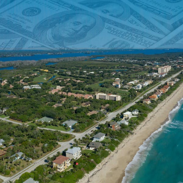 A Florida beach with hundred dollar bills superimposed over the sky