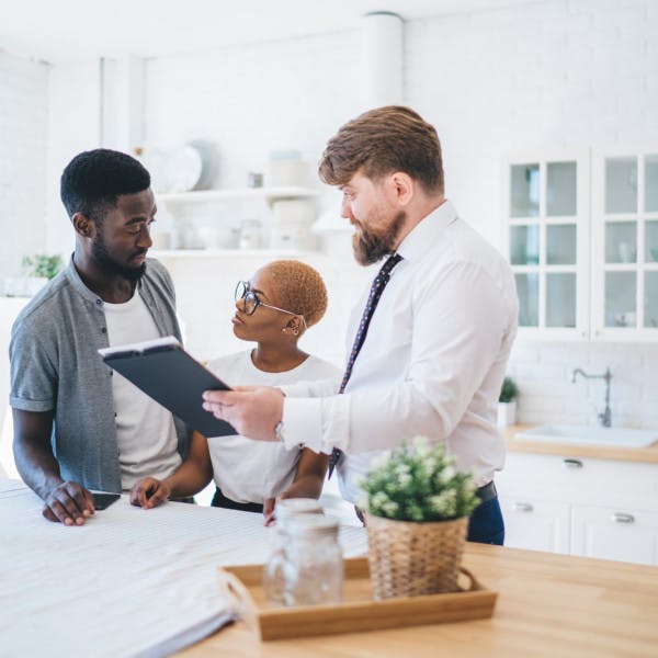 A real estate agent shows a home to a young Black couple