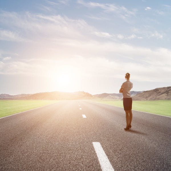 Businesswoman looking down country road 