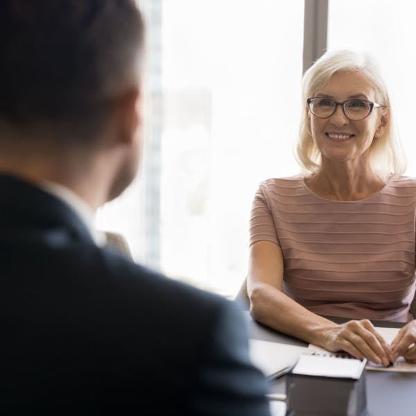 An older female real estate agent talks to a team leader about joining the firm