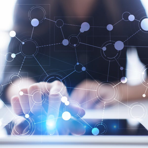 A woman taps a tablet with a network of connected nodes represented above it