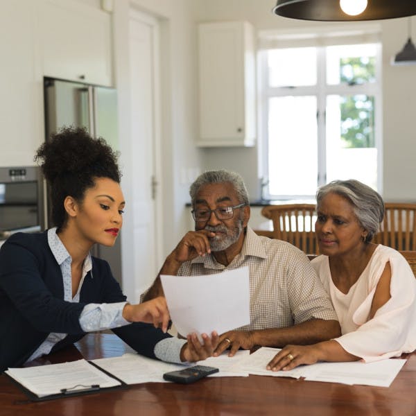 A Black female real estate agent showing a contract to an older Black couple