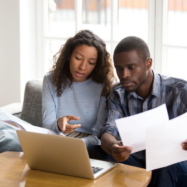 An African American couple look at financial options on their laptop