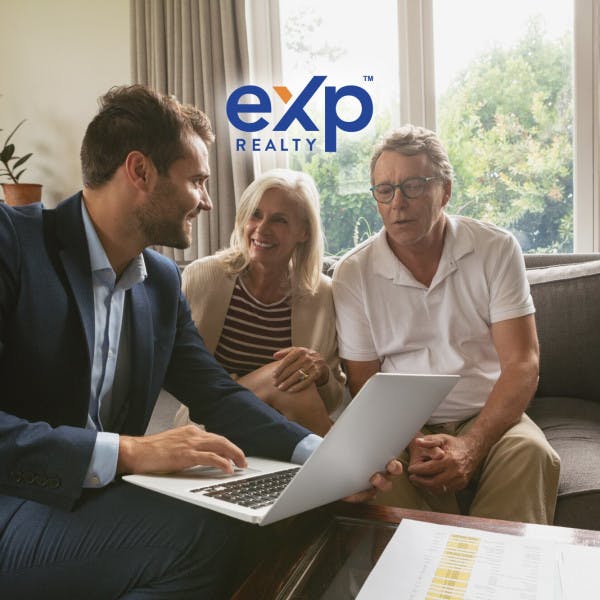 A real estate agent reviews information with home sellers, and the eXp Realty logo