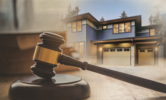 A gavel against a backdrop of a house.