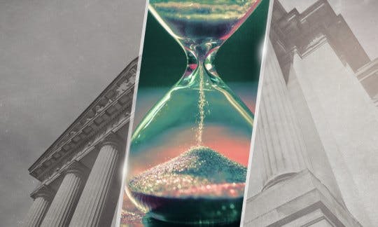Sand runs through an hourglass against a backdrop of courthouse columns